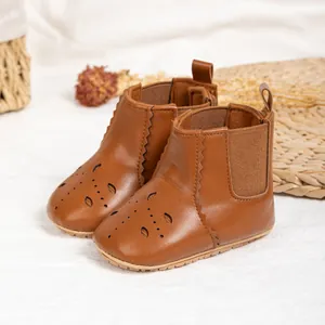 Detail of brown baby boots with floral cut-out patterns and non-slip rubber soles