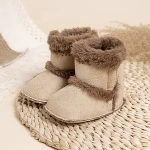 Gros plan de bottes de neige beige pour bébé avec bordure en fourrure sur un tapis de paille