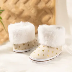 Detail of beige baby snow boots with white faux fur trim and gold star patterns