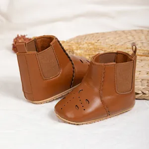 Brown baby Chelsea boots with hollow teardrop patterns and non-slip rubber soles