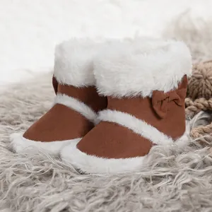 Detail of warm baby winter boots with fluffy white fur trim and decorative bow accent