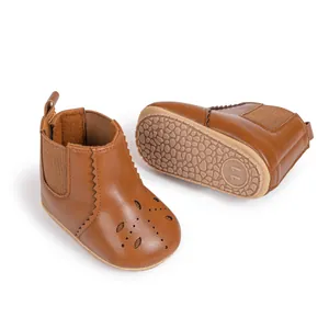 Detail of brown leather baby Chelsea boots with hollow perforations and anti-slip rubber sole