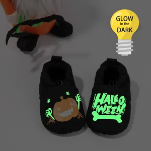 Detailed view of glow in the dark Halloween baby shoes with pumpkin and spider web motifs