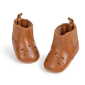 Detail of caramel baby boots with flower perforations and elastic side bands