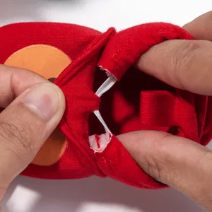 Close-up of elastic ankle band on red baby shoes showing high stretch and flexibility