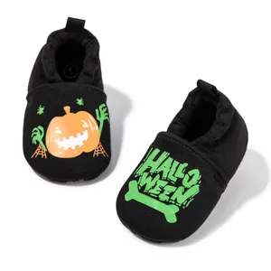 Detail of baby Halloween soft-sole shoes with pumpkin and skull print on black knit fabric