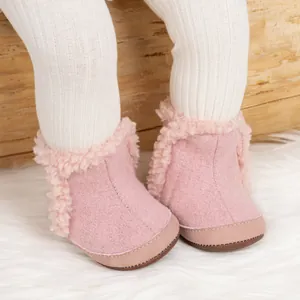 Primer plano de botas de nieve rosas para bebé con forro de pelo y suela de goma antideslizante