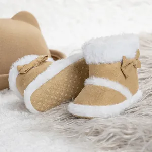 Camel baby winter boots with bows, faux fur trim and matching bear ear hat on soft rug