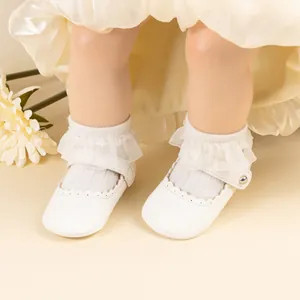 Détail de chaussures bébé Mary Jane blanches avec chaussettes à dentelle et volants