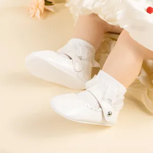Gros plan de babies en cuir verni blanc avec chaussettes en dentelle et bord festonné