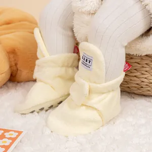 Close-up of beige plush baby walker shoes with non-slip soles and warm faux fur