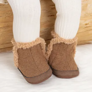 Detalle de botas de nieve marrones para bebé con ribete de pelo sintético y forro suave