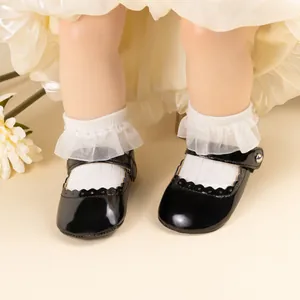 Détail de chaussures Mary Jane pour bébé en cuir verni noir avec bords festonnés