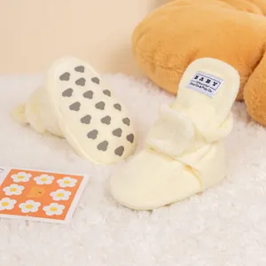 Detail of baby winter shoes with non-slip heart patterns and soft yellow plush material