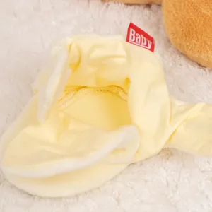 Close-up of soft yellow baby sock shoe with plush lining and red Baby brand tag