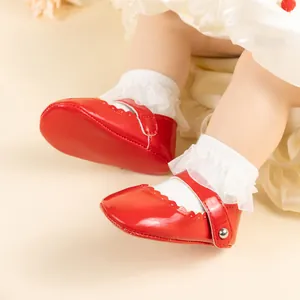 Détail de chaussures bébé Mary Jane en cuir verni rouge avec bords festonnés et velcro