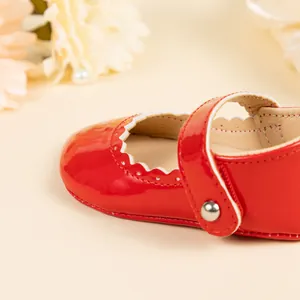 Détails de chaussures bébé en cuir verni rouge avec bords festonnés et boucle métal