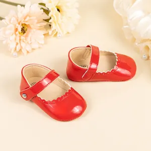 Vue détaillée des chaussures bébé en cuir verni rouge avec bords festonnés et boucle