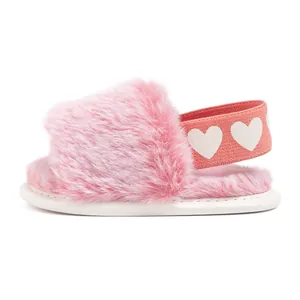 Close-up of pink plush baby slippers with white heart printed elastic heel strap
