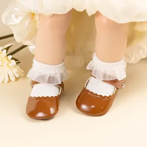 Détail de chaussures bébé Mary Jane en cuir verni marron avec chaussettes dentelle