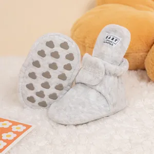 Detail of light grey baby walking shoes with anti-slip cloud pattern soles and plush texture