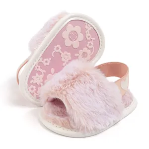 Detail of pink plush baby slippers showing non-slip soft sole and heart elastic strap