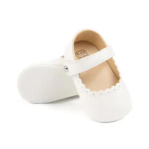 Détail de chaussures bébé Mary Jane blanches avec bords festonnés et bride velcro