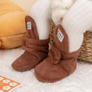 Close-up of brown plush baby walking boots with white BABY label and soft knit socks