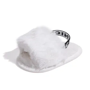 Detail of white plush baby slipper featuring a 'NICE' elastic strap and soft fabric sole