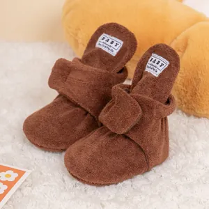 Close-up of brown plush baby boots on white rug showing soft fleece texture and tag