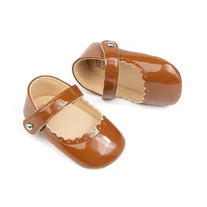 Détail de chaussures Mary Jane marron en cuir verni pour bébé avec bords ondulés et boucle