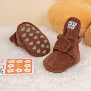 Detail of baby winter shoes showing grey non-slip silicone paw patterns on soft cotton soles