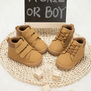 Detailed view of baby khaki boots with velcro and lace-up closure on woven mat