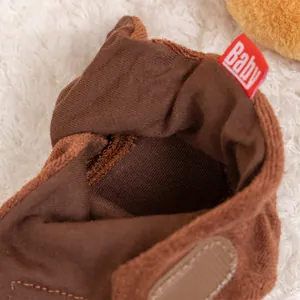 Detail of warm brown plush baby booties with adjustable velcro strap and Baby label