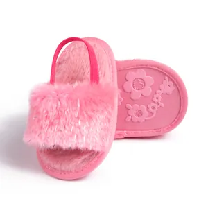 Detail view of pink baby plush slippers showing floral non-slip soles and elastic heel straps