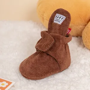 Close-up of brown plush baby walking shoe with secure hook and loop strap detail