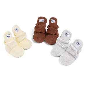 Close-up of soft cotton baby walking boots in beige, brown and grey with velcro straps