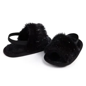 Close-up of black fuzzy baby slippers with silver glitter and elastic back strap