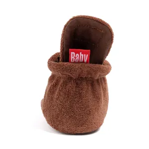 Detail showing the plush brown fabric texture and red Baby label of the infant walker shoe