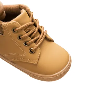Detailed close-up of kids tan faux leather shoes with durable rubber soles and round laces