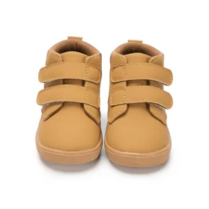 Detail of brown children's mid-top boots featuring double Velcro straps and durable rubber soles