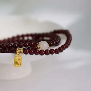 Three-layer garnet bead bracelet with white accent and gold Fu lucky charm pendant