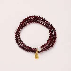 Deep red garnet wrap bracelet with white jade bead and golden Chinese Fu luck charm