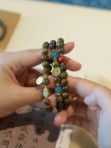 Macro shot of sandalwood beads bracelet with golden gourd pendant and Fu charm detail