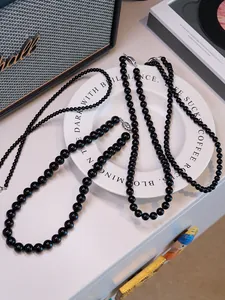 Close-up of black agate beaded necklaces with silver lobster clasps on a stylish desk