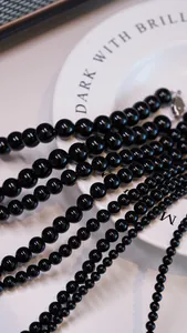 Close-up of natural black agate beaded necklaces with silver lobster clasps on a white tray