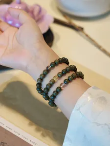 Detailed macro shot of three green sandalwood bracelets with crystal beads on a wrist