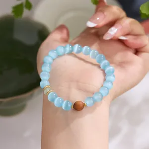 Glacial blue cat-eye stone bead bracelet with sandalwood accents and gold gear spacers