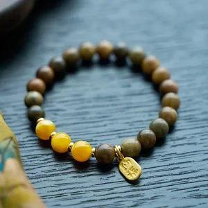 Macro shot of sandalwood beads bracelet with Hetian jade gourd and Nafu charm detail