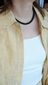 Close-up of natural black agate beaded necklace worn by a model in a casual yellow shirt